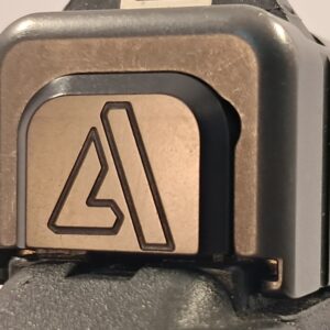 Custom black finish slide cover plate for a Glock pistol featuring a stylized triangle 'A' logo, shown in a close-up rear view