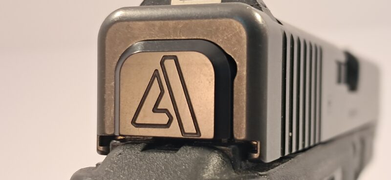 Custom black finish slide cover plate for a Glock pistol featuring a stylized triangle 'A' logo, shown in a close-up rear view