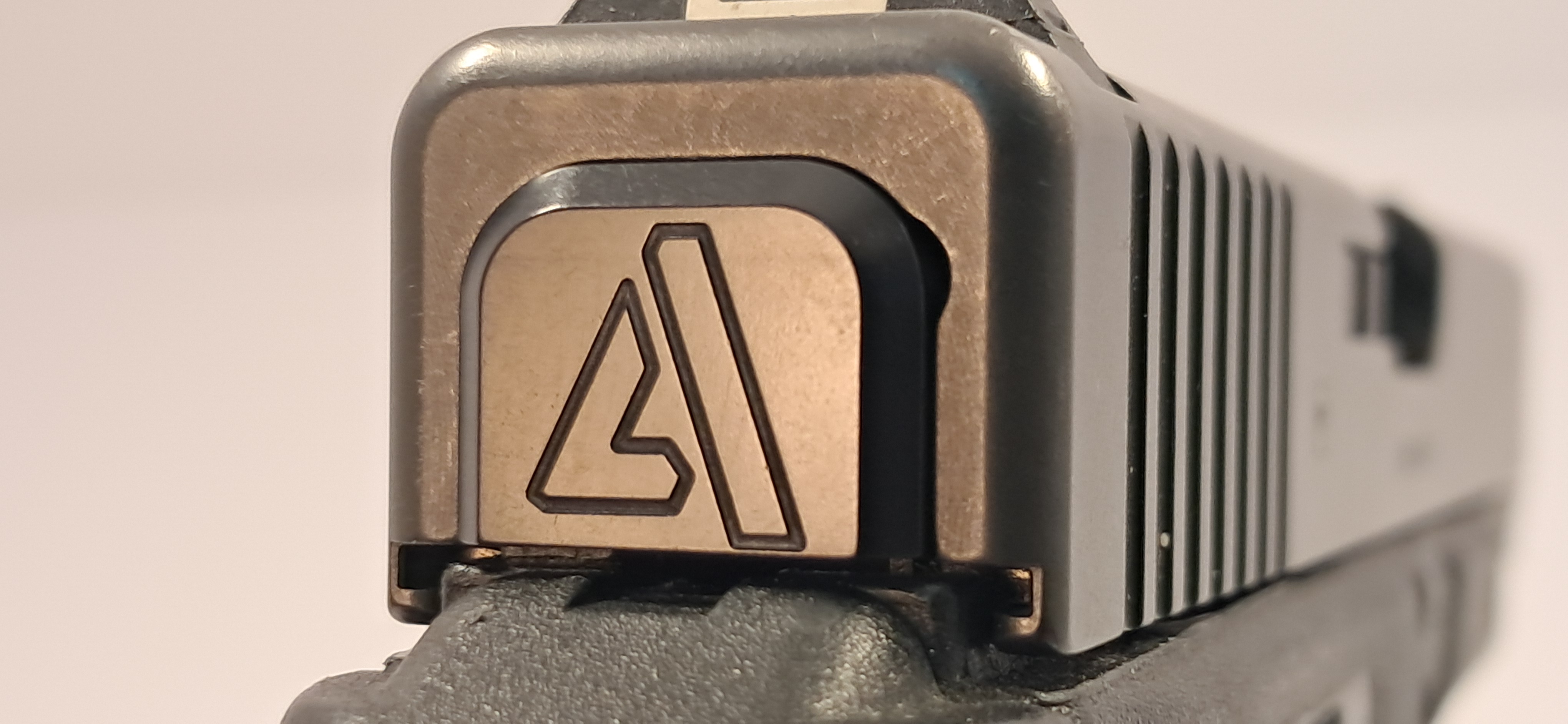 Custom black finish slide cover plate for a Glock pistol featuring a stylized triangle 